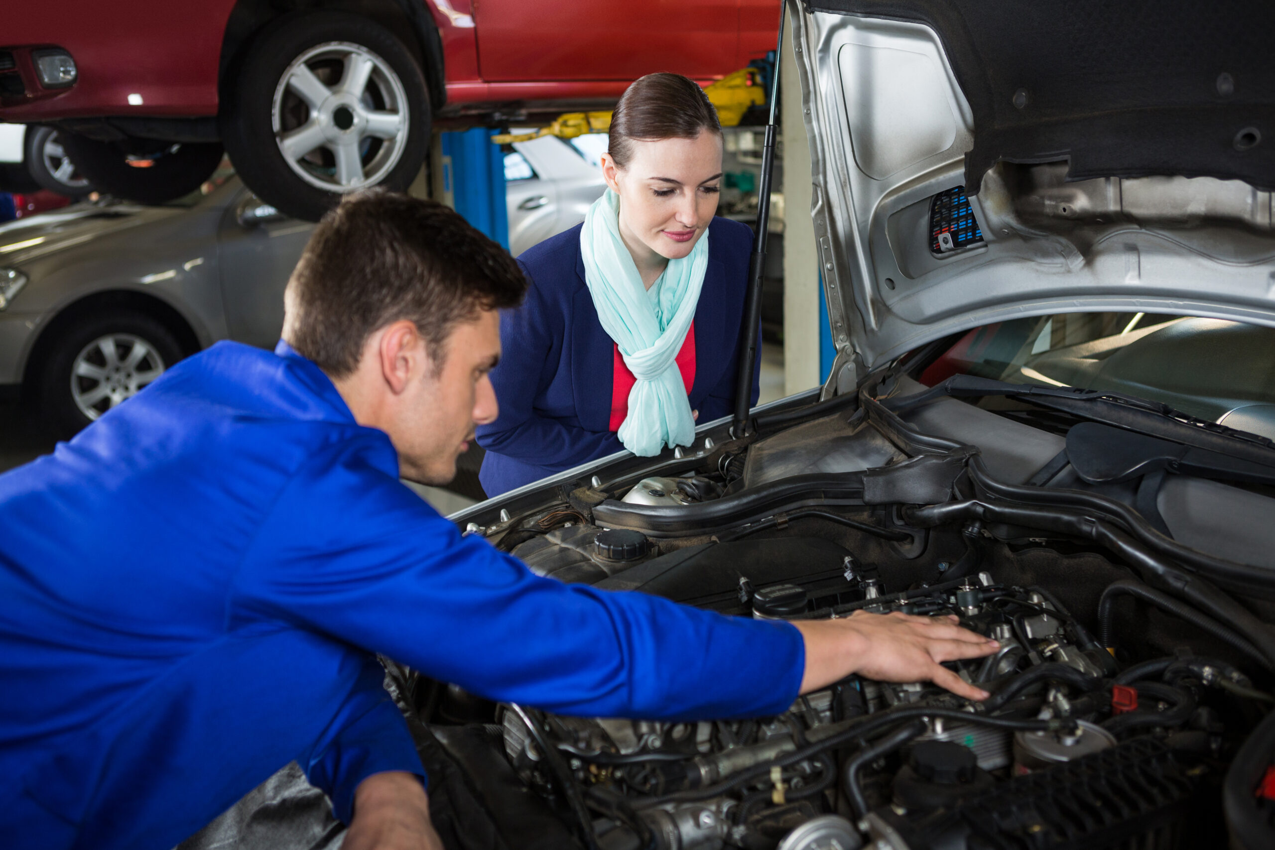 Mechanic showing customer the problem with car at repair garage